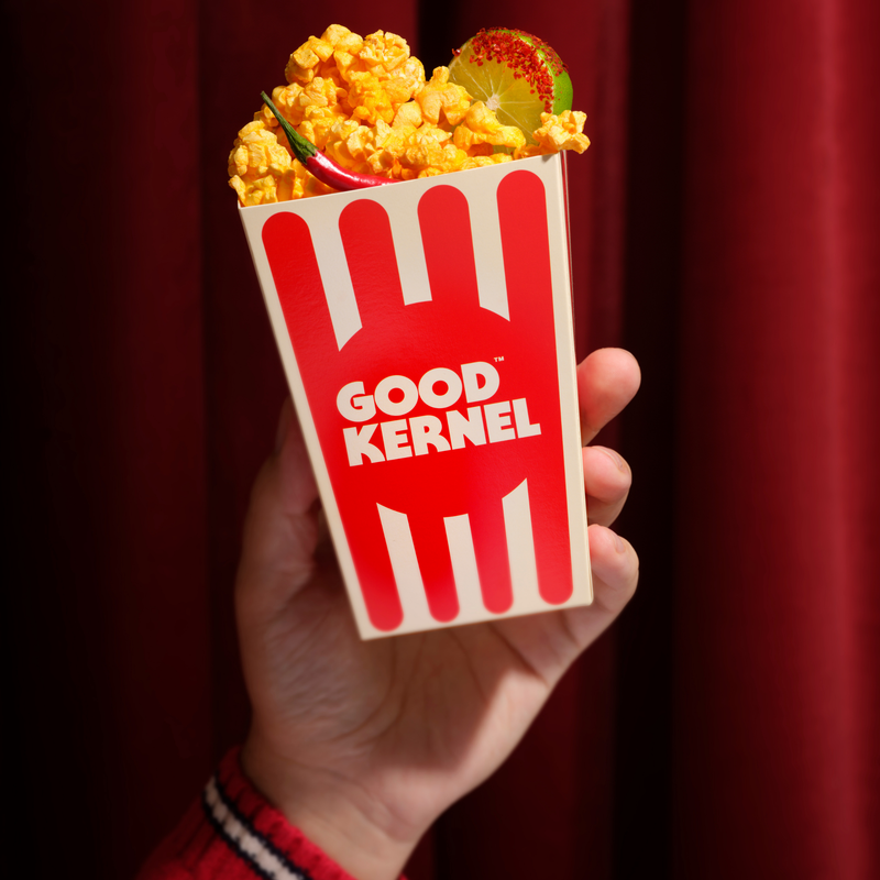 Hand holding a Good Kernel popcorn bucket filled with Chili Lime popcorn